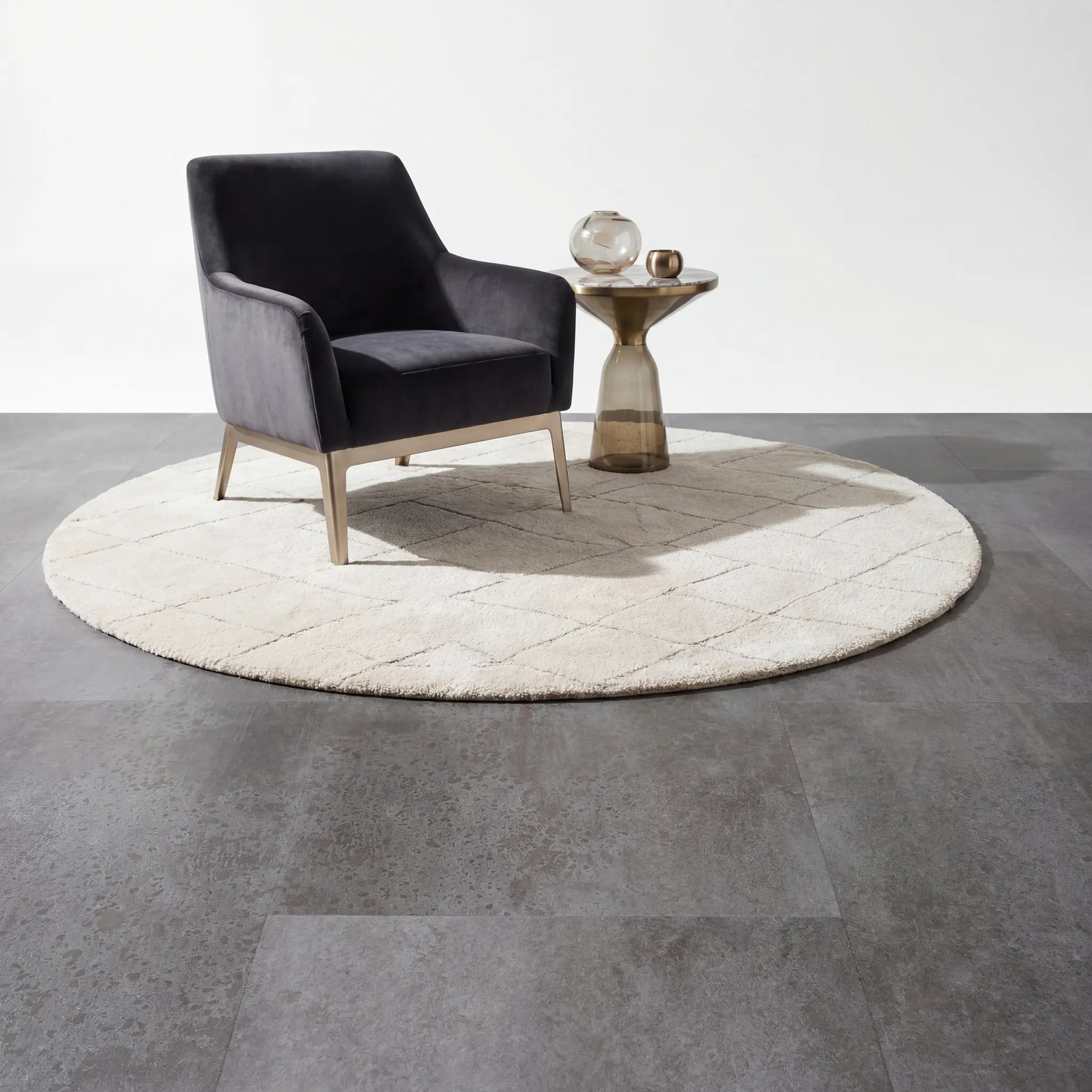 Designfauteuil en rond tapijt op Aura Terrena Griseus betonlook plak pvc vloer.