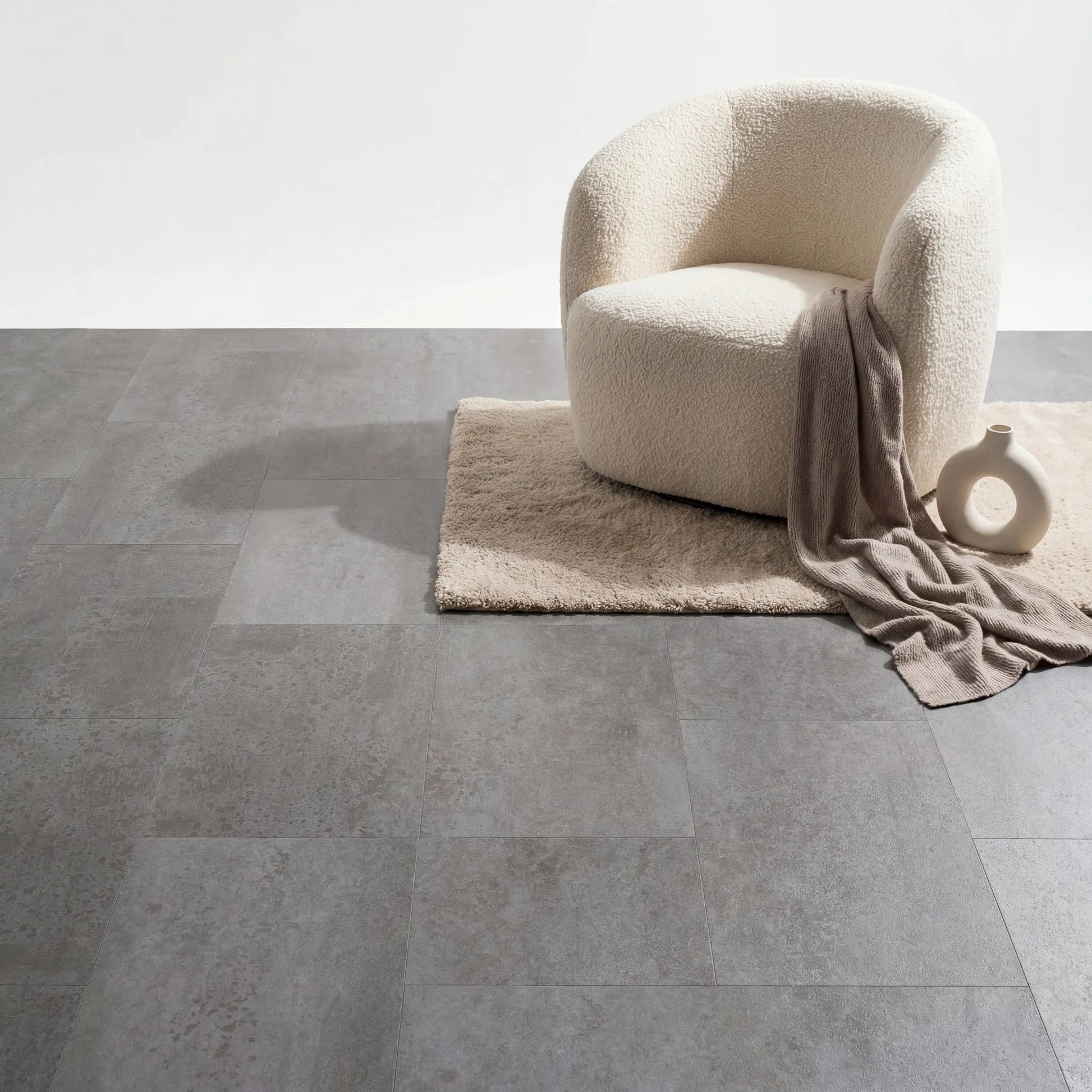 Boucle stoel en beige vloerkleed op Aura Terrena Griseus betonlook plak pvc vloer.